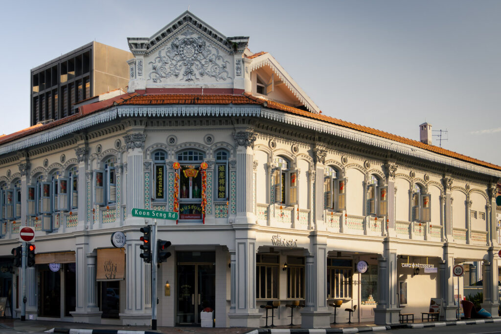Ornate white two-storey Peranakan corner building with decorative columns, housing a café and a Peranakan museum.
