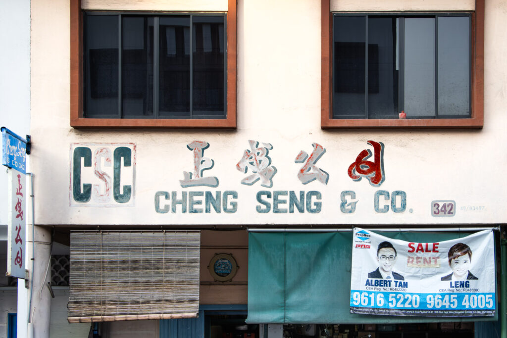 Faded shopfront sign reading 'Cheng Seng & Co' with a real estate for-sale banner hanging below the windows.