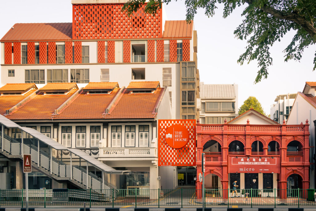 Red-tiled heritage bakery building beside a modern condominium with a red geometric-patterned facade.